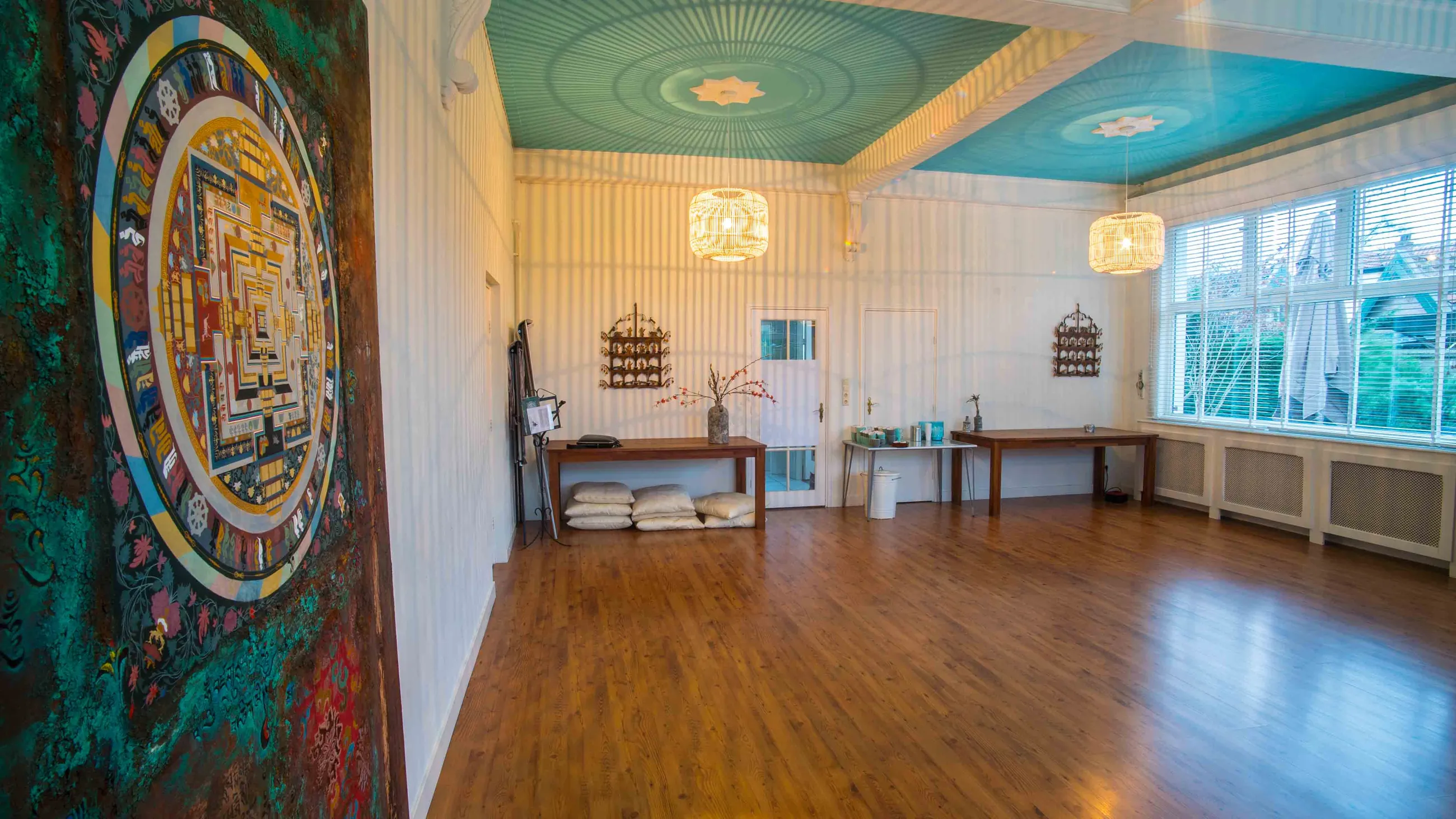 De grote presentatiezaal vanaf de andere kant, met een grote ronde mandala op de wand en het turkooise plafond erboven.